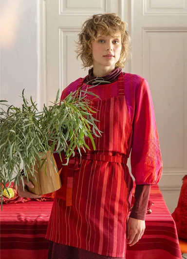 A tablescape in warm hues with flowers and red textiles from Gudrun Sjödén’s Alaska Home collection.