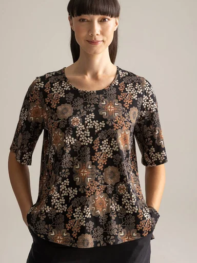 A woman wearing a patterned top from Gudrun Sjödén.