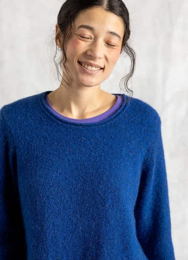 A woman wearing a beige knitted cardigan from Gudrun Sjödén.
