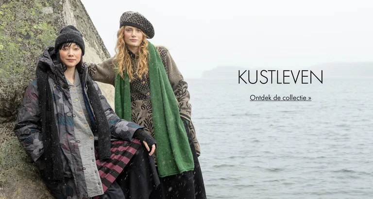 Twee vrouwen poseren tegen een rots aan het water met kleding en accessoires uit de wintercollectie 2025 van Gudrun Sjödén. 