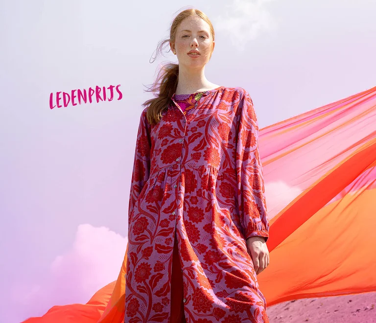 Een foto van een vrouw die een donkerroze vest over een roze jurk van Gudrun Sjödén draagt.