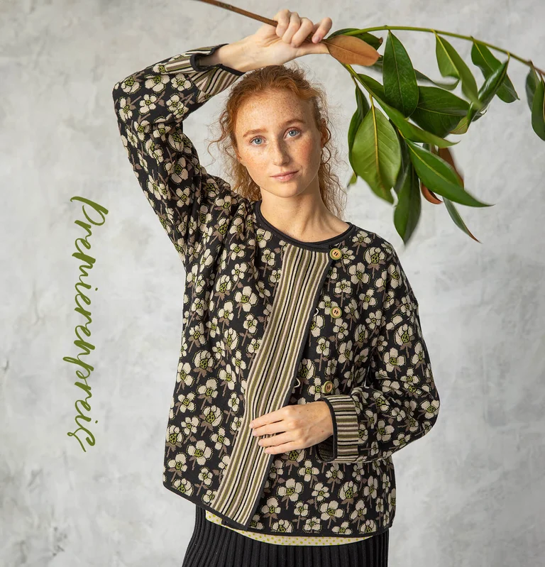 Eine Frau in einer floralen schwarzen Strickjacke von Gudrun Sjödén. 