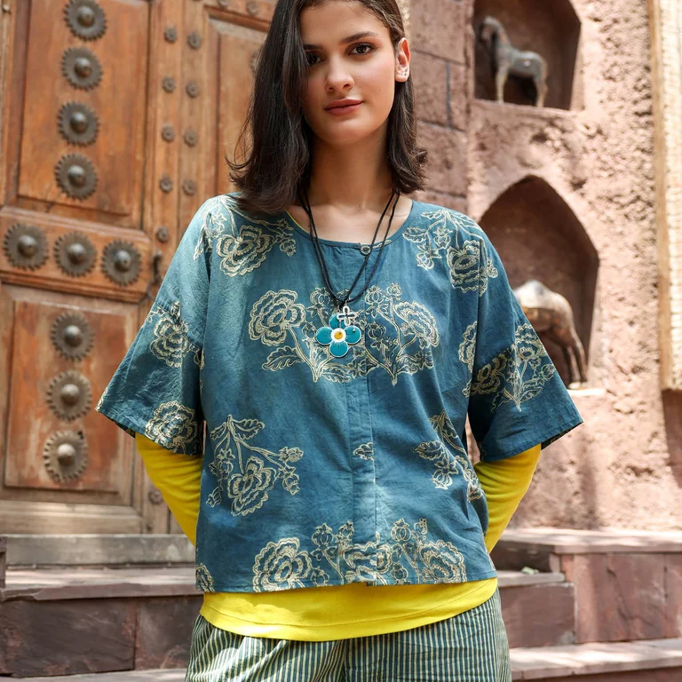A woman wearing a blue, short-sleeve blouse and striped trousers from Gudrun Sjödén. 