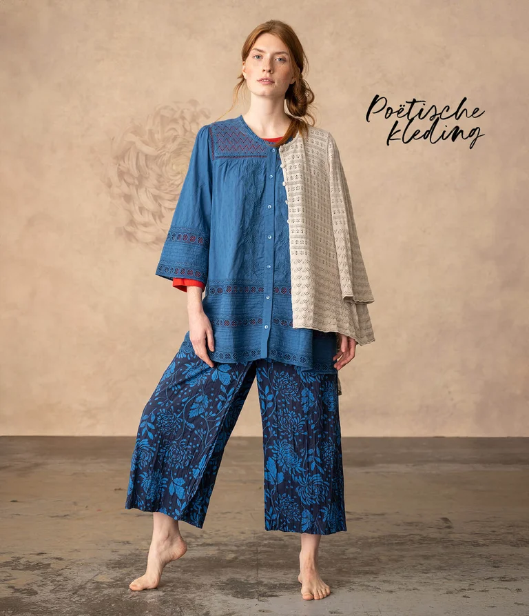 A woman wearing a blue blouse and patterned blue pants from Gudrun Sjödén.