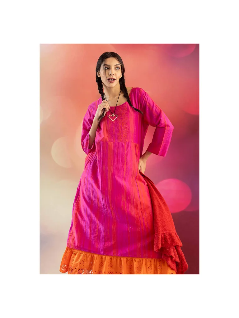 A woman wearing a pink, shimmering dress and a silver necklace from Gudrun Sjödén’s 2025 Christmas collection. 