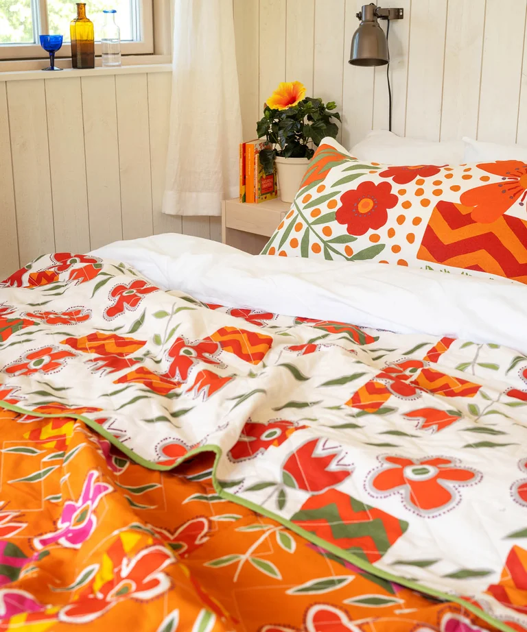 Closeup of a quilted bedspread from Gudrun Sjödén with red flowers.