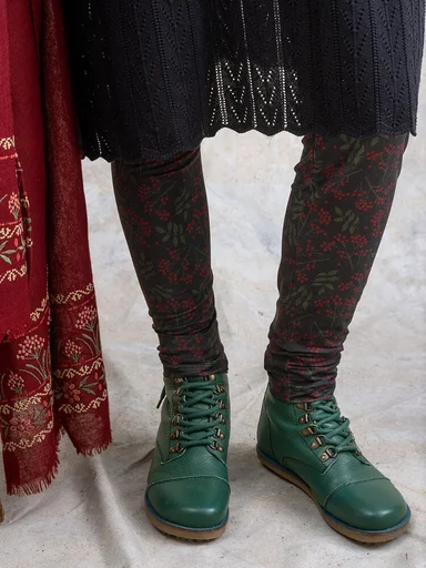 Eine Frau in  gemusterten Leggings und grünen Stiefeletten von Gudrun Sjödén.