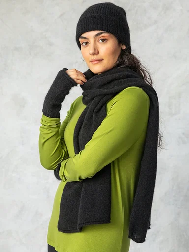 A woman wearing a black beanie, scarf and fingerless gloves from Gudrun Sjödén. 