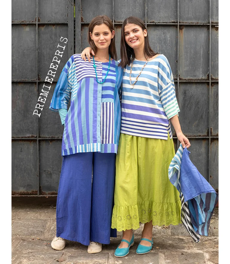 Two women wearing striped clothes from Gudrun Sjödén. One woman is holding a matching scarf in her hand.