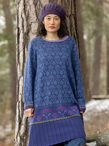 Eine Frau in einem blauen Strickkleid von Gudrun Sjödén. 