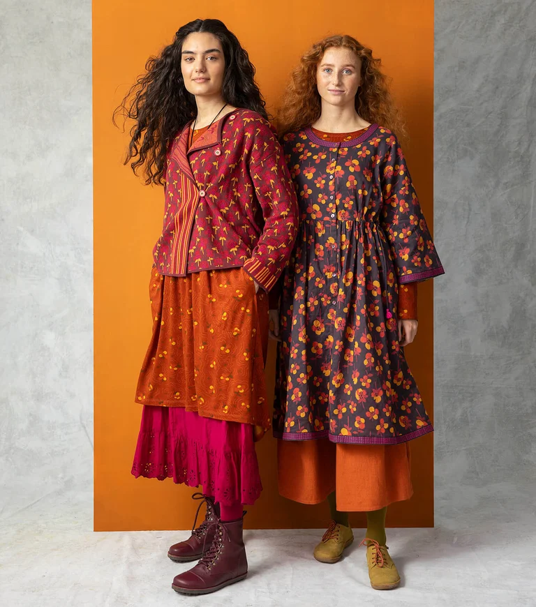 Two women wearing patterned clothes in warm hues from Gudrun Sjödén. 
