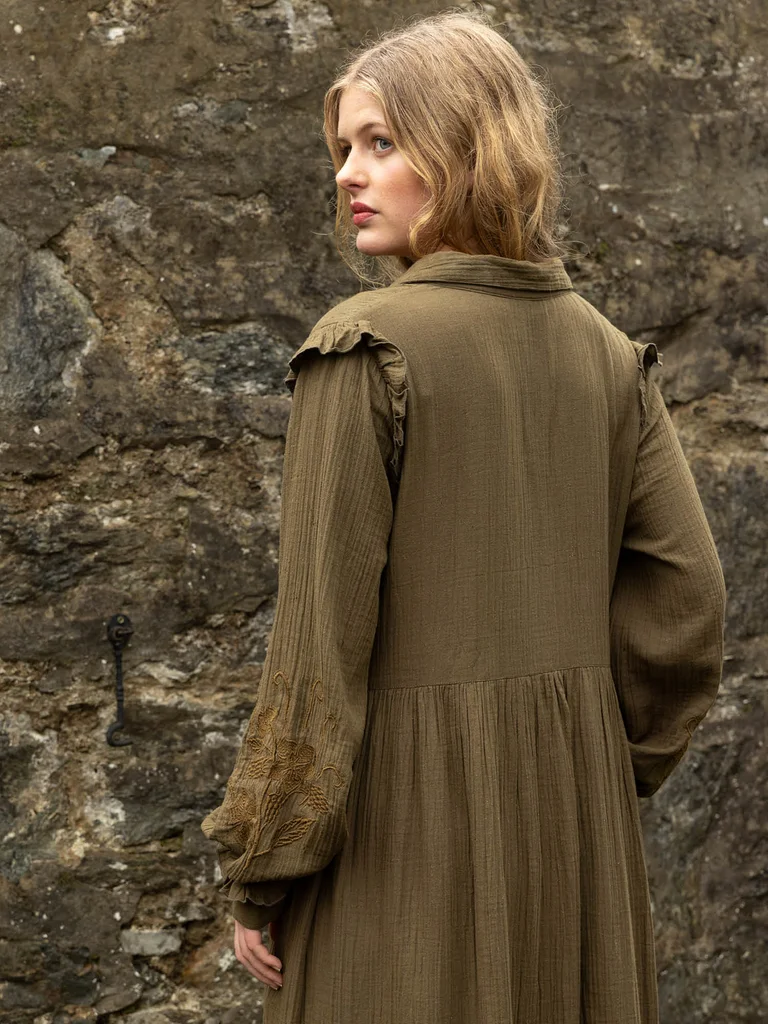A woman with her back to the camera wearing a woven green dress from Gudrun Sjödén.