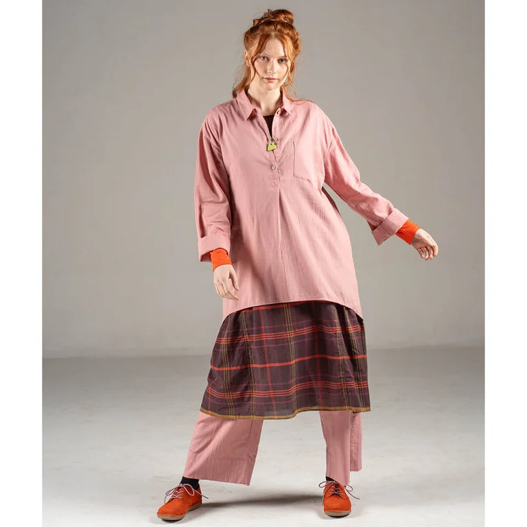 Une femme portant une chemise et un pantalon roses signés Gudrun Sjödén. 