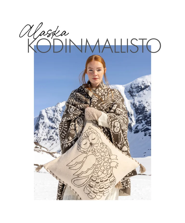 A woman standing in a snowy landscape wrapped in a blanket, holding a cushion, from Gudrun Sjödén’s 2025 Christmas Home collection. 