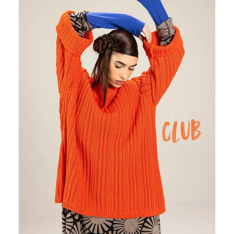 A woman wearing a bright orange knitted sweater from Gudrun Sjödén.