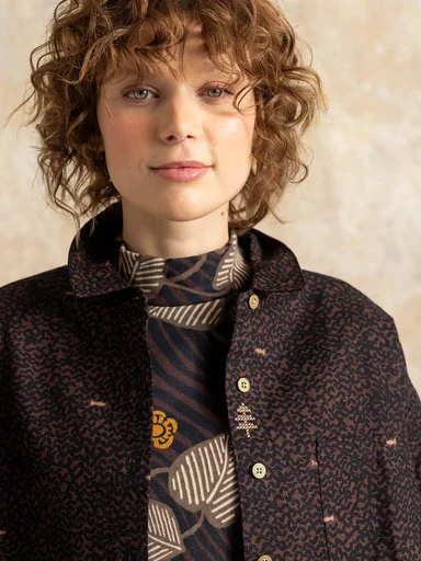A closeup of a woman wearing layers of patterned brown clothing from Gudrun Sjödén.