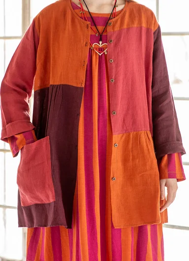 A woman wearing a brown blouse over a striped dress from Gudrun Sjödén. 