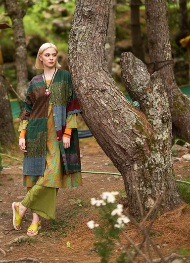 An upper body wearing layers of patterned clothes from Gudrun Sjödén.