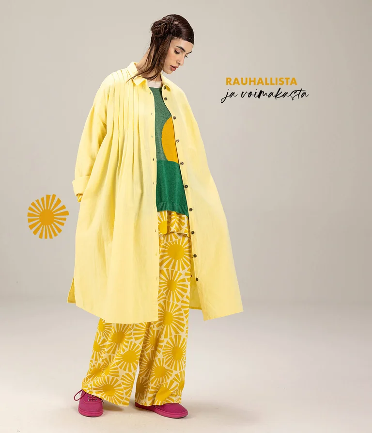 A woman wearing yellow and green clothing in layers from Gudrun Sjödén. 