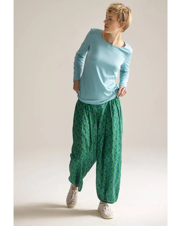 A woman wearing a blue sweater and patterned trousers from Gudrun Sjödén.