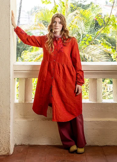 A woman wearing a red dress with embroidery from Gudrun Sjödén. 