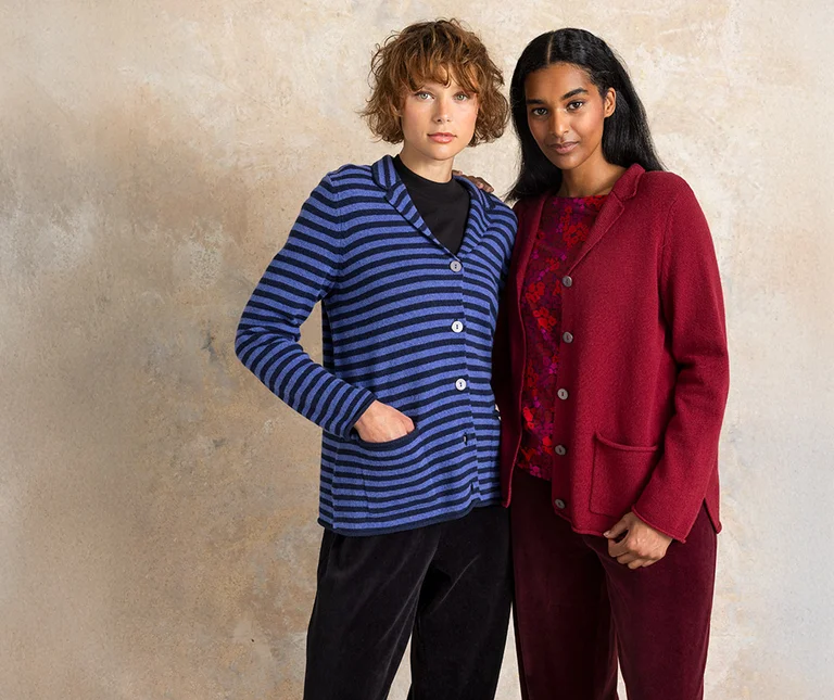 Two women wearing knit blazers from Gudrun Sjödén, one is blue striped, the other is red.