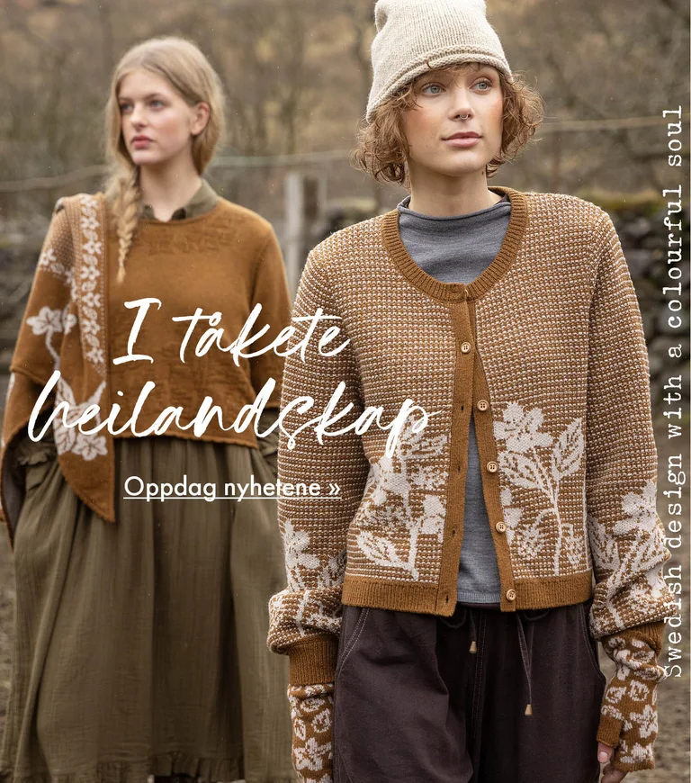 Two women standing next to each other wearing clothes in earthy hues from Gudrun Sjödén. Sheep and a stone wall are visible in the background.