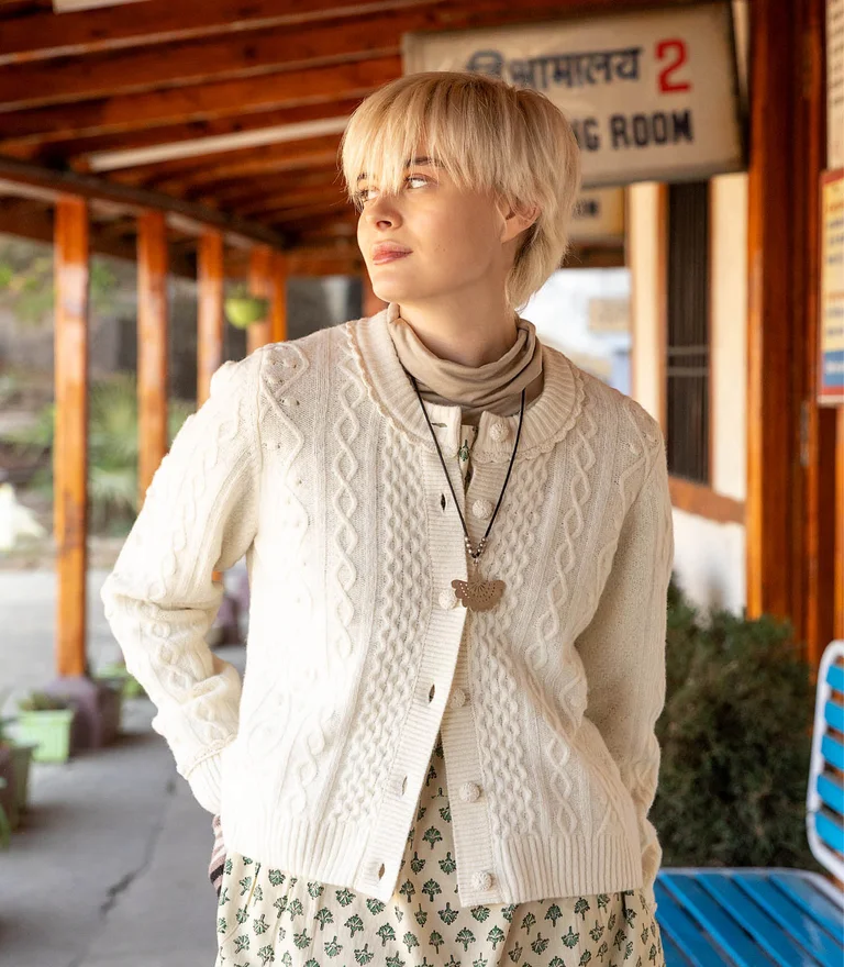 A woman wearing a white, cable-knit cardigan in lambswool from Gudrun Sjödén.
