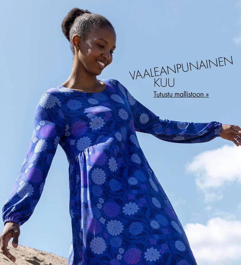 Sinisen taivaan alla seisova nainen, joka on pukeutunut Gudrun Sjödénin siniliilaan, kuviolliseen mekkoon.