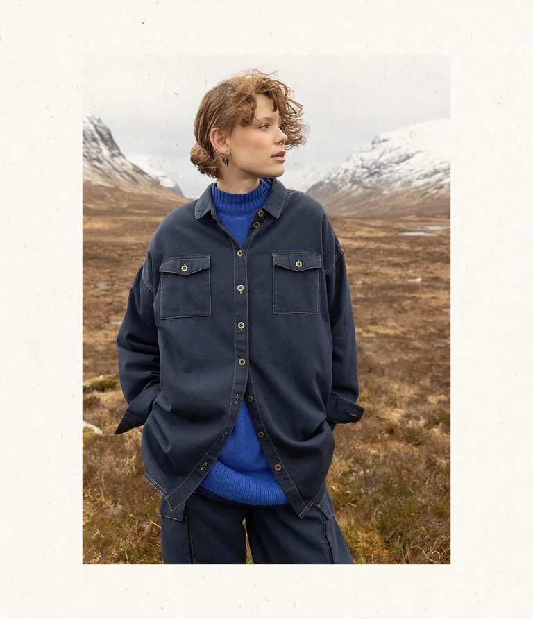 A woman in a mountain setting wearing clothing with a denim feel from Gudrun Sjödén.