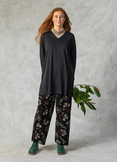 A woman wearing a black tunic and patterned velour trousers from Gudrun Sjödén.