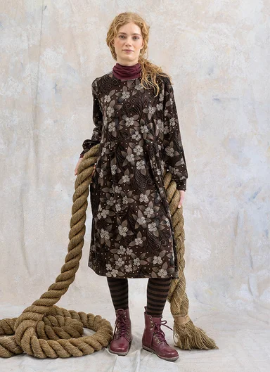 Eine Frau in einem gemusterten Kleid von Gudrun Sjödén. 