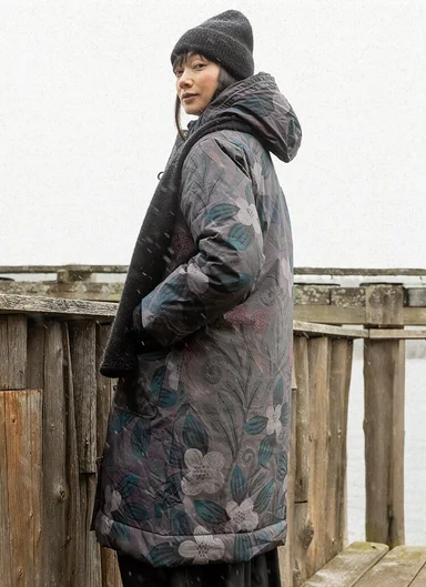 Eine Frau in einer geblümten Winterjacke von Gudrun Sjödén. 