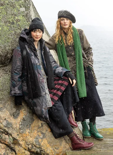 Two women standing leaning against a rock wearing clothes from Gudrun Sjödén. 