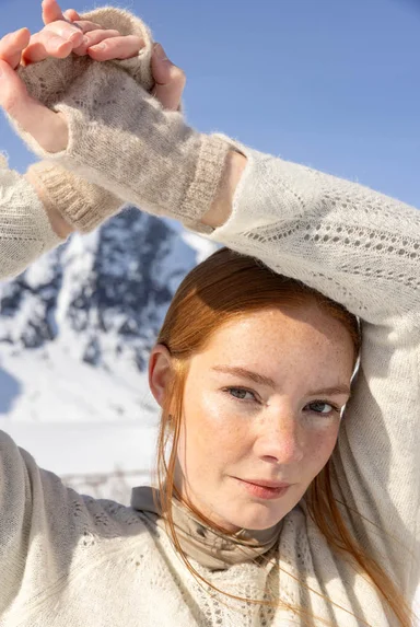Eine Großaufnahme einer Frau in weißer Strickmode aus Gudrun Sjödéns Weihnachtskollektion 2025.