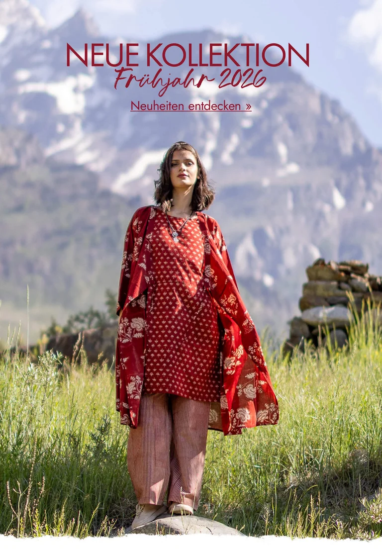 Eine Frau steht in einer Berglandschaft. Sie trägt Lagenlook aus roter Webware von Gudrun Sjödén.