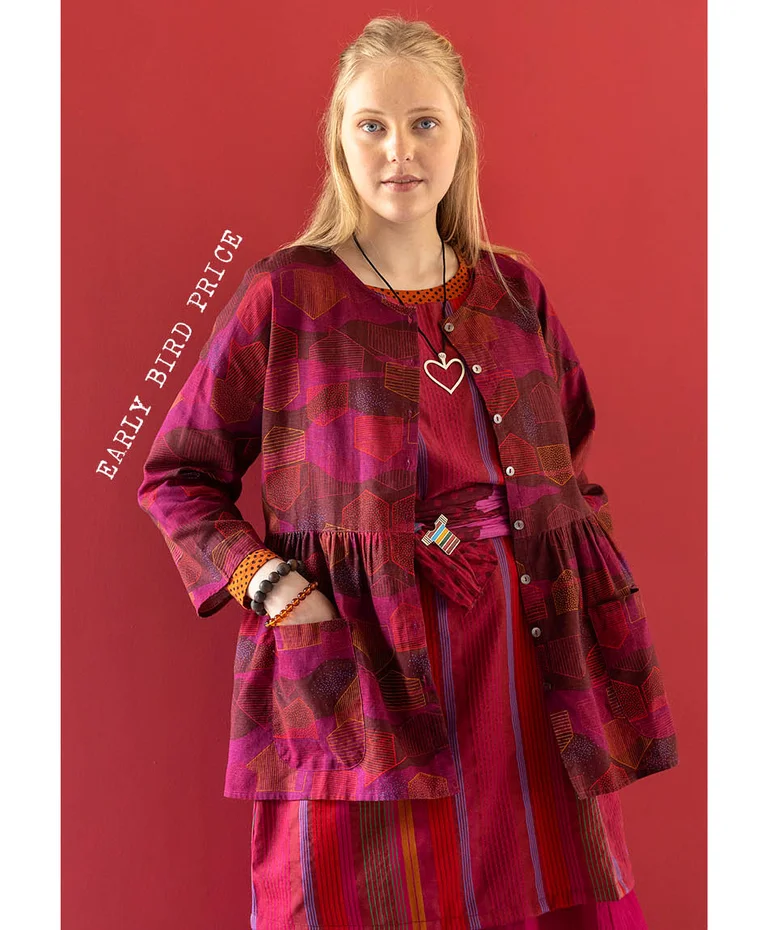 A woman wearing a button-up pink-red blouse from Gudrun Sjödén’s 2025 Christmas collection. 
