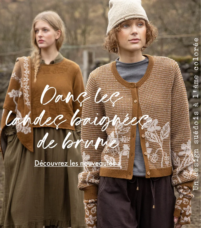 Two women standing next to each other wearing clothes in earthy hues from Gudrun Sjödén. Sheep and a stone wall are visible in the background.