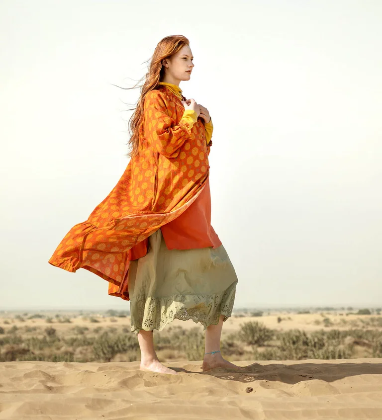 A woman wearing a patterned orange dress from Gudrun Sjödén.