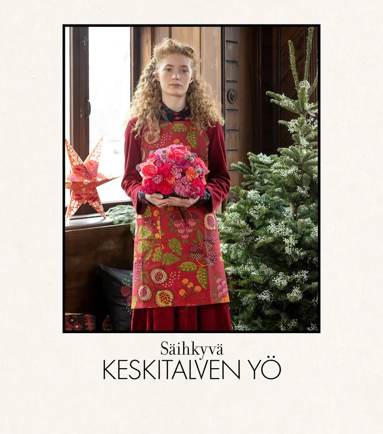 A woman wearing a patterned apron from Gudrun Sjödén.