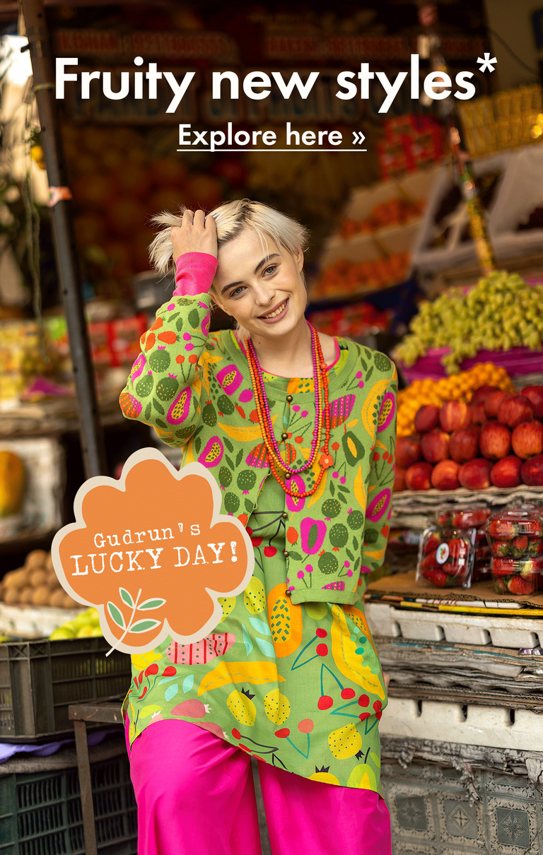 A collage of a woman standing with lots of fruit, wearing clothes from Gudrun Sjödén printed with brightly-coloured fruit patterns.