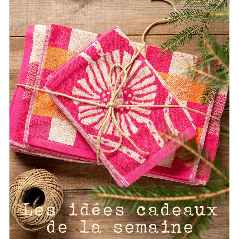 Des serviettes-éponges de différentes tailles signées Gudrun Sjödén, empilées et entourées d'un ruban cadeau.