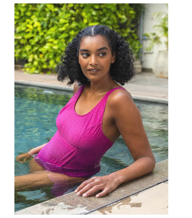 A woman in a pool wearing a pinkish purple swimsuit from Gudrun Sjödén.