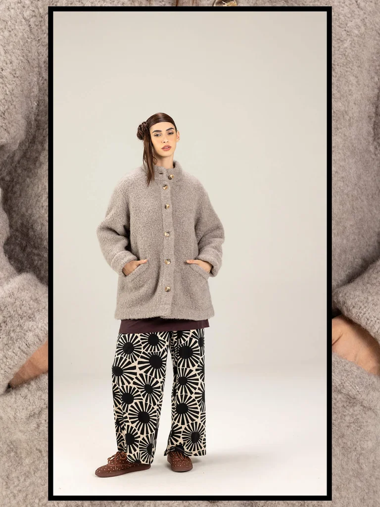 A woman wearing a beige wool jacket and a pair of black and white patterned pants from Gudrun Sjödén.