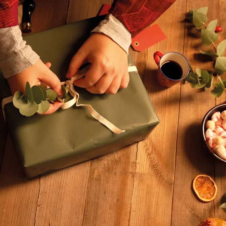 Linten om een kerstcadeau in natuurlijke kleuren met dennentakken en gedroogde sinaasappels.