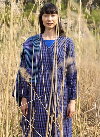 A woman in front of a rock face wearing layers of clothes from Gudrun Sjödén.
