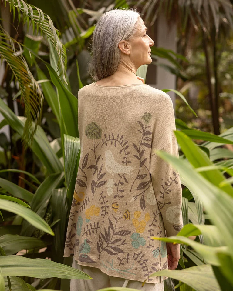 A woman wearing a patterned beige knitted sweater from Gudrun Sjödén.