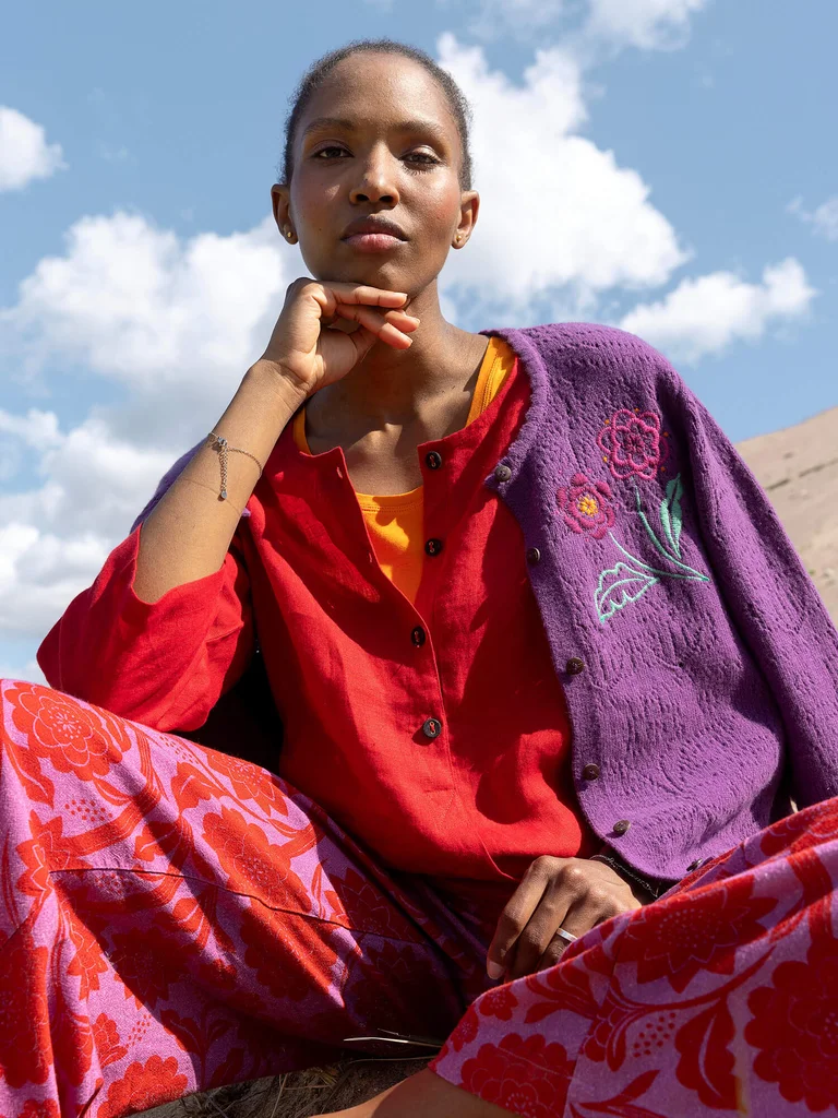 A woman wearing an embroidered cardigan and floral pants from Gudrun Sjödén. 