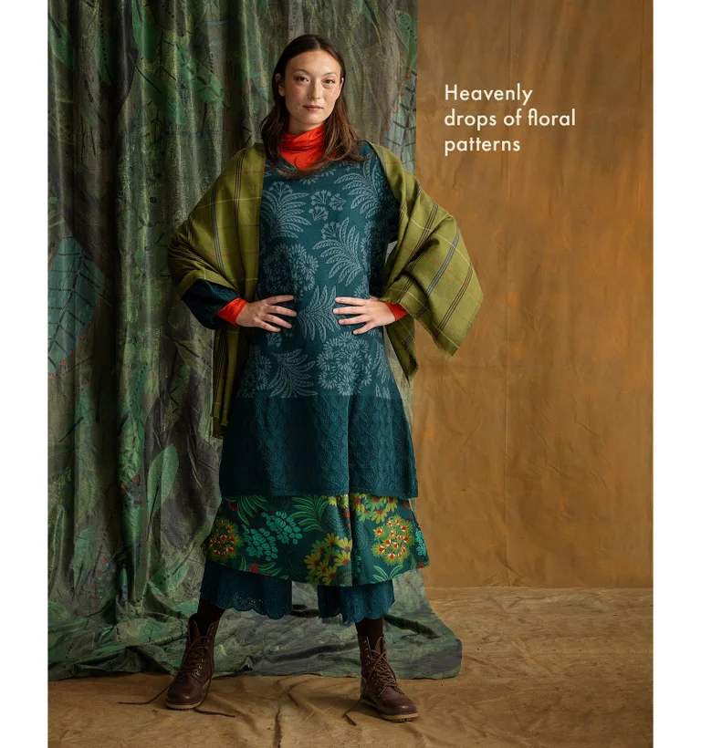 A woman with her hands at her sides wearing layers of clothing from Gudrun Sjödén.