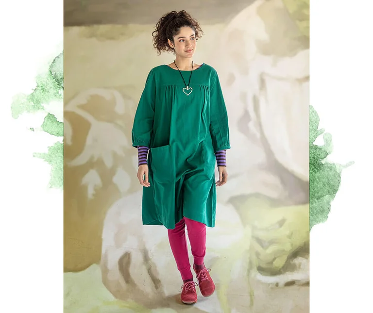 A woman wearing a green woven dress and pink leggings from Gudrun Sjödén.